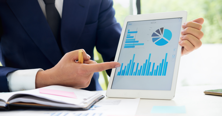 Business professional presenting a legal spend analytics dashboard with charts showing invoice savings, legal spend reporting, and performance metrics on a tablet.