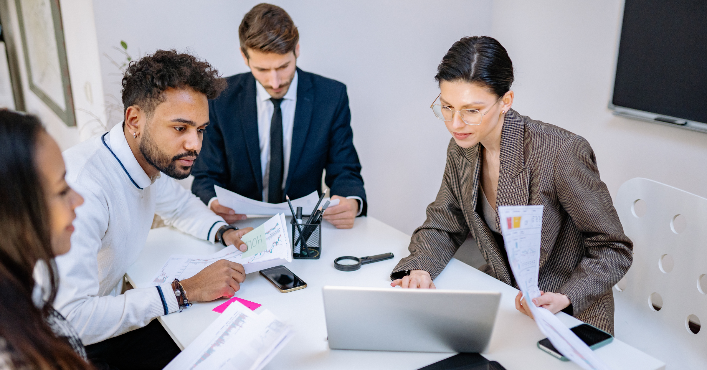 Business team reviewing data and reports together around a laptop during a meeting.